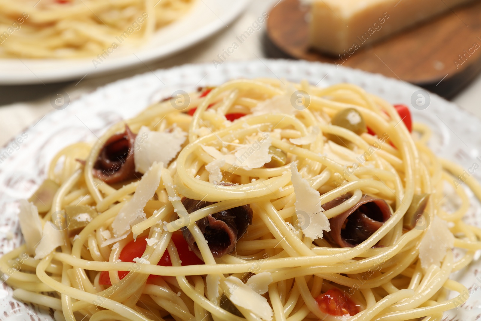 Photo of Delicious pasta with anchovies, tomatoes and parmesan cheese on table, closeup