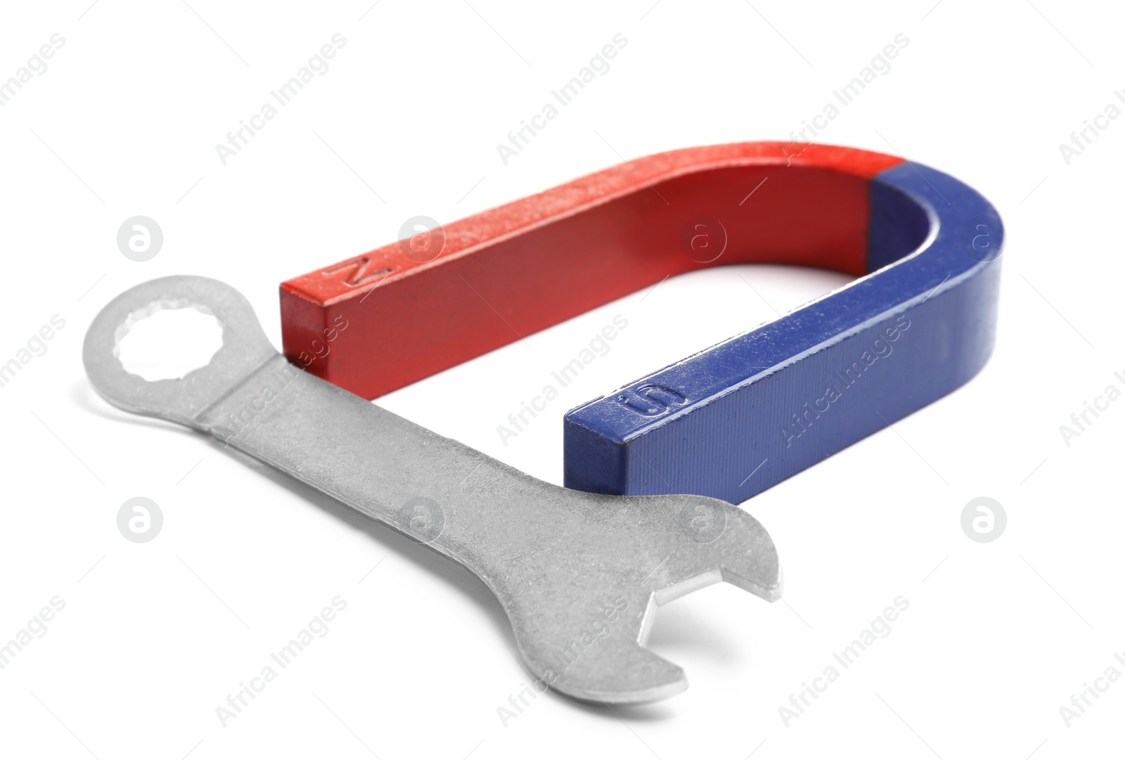 Photo of Horseshoe magnet attracting wrench on white background