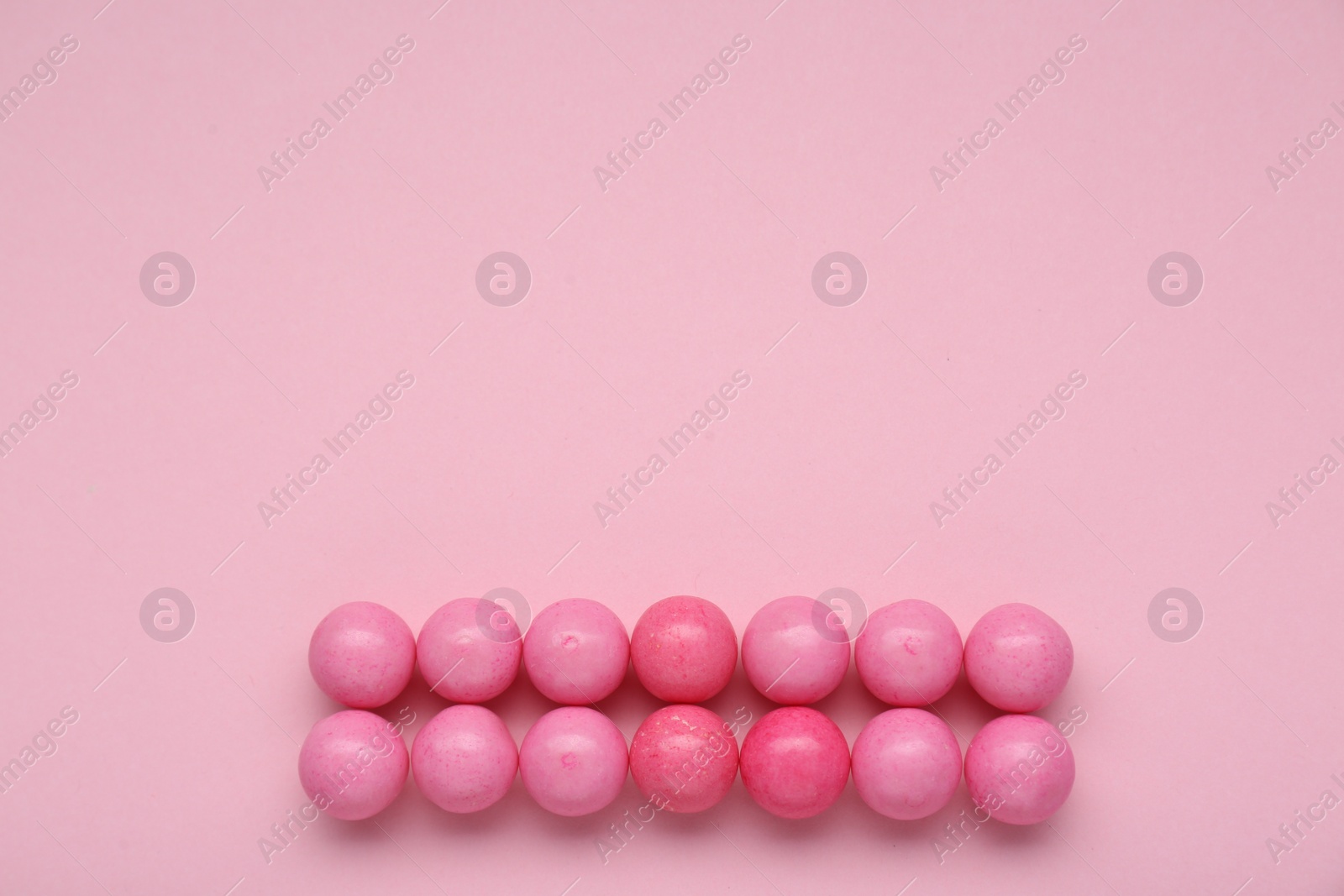 Photo of Many bright chewy gumballs on pink background, flat lay. Space for text