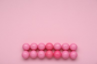 Many bright chewy gumballs on pink background, flat lay. Space for text