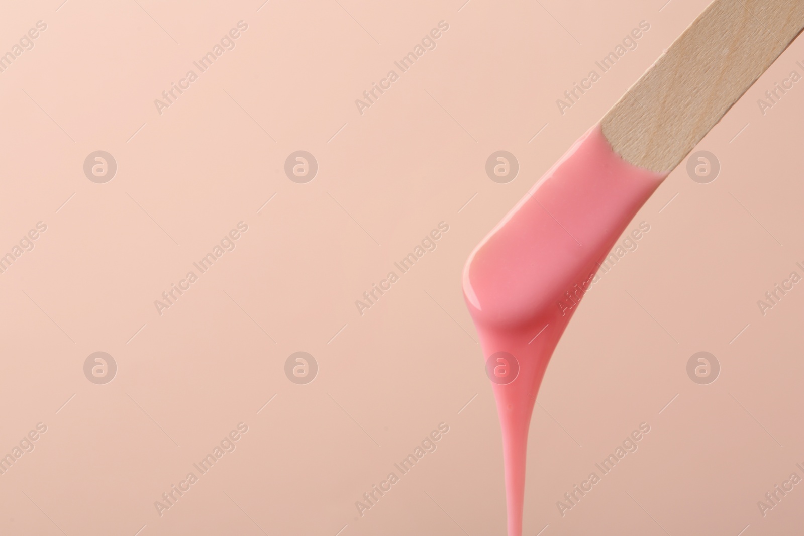 Photo of Wooden spatula with hot depilatory wax on beige background. Space for text