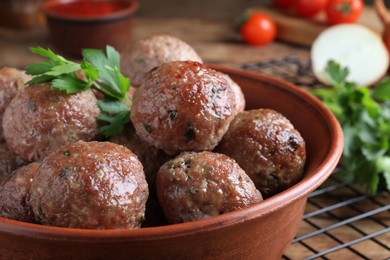 Photo of Tasty cooked meatballs with parsley in bowl, closeup