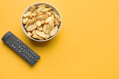 Remote control and rusks on yellow background, flat lay. Space for text