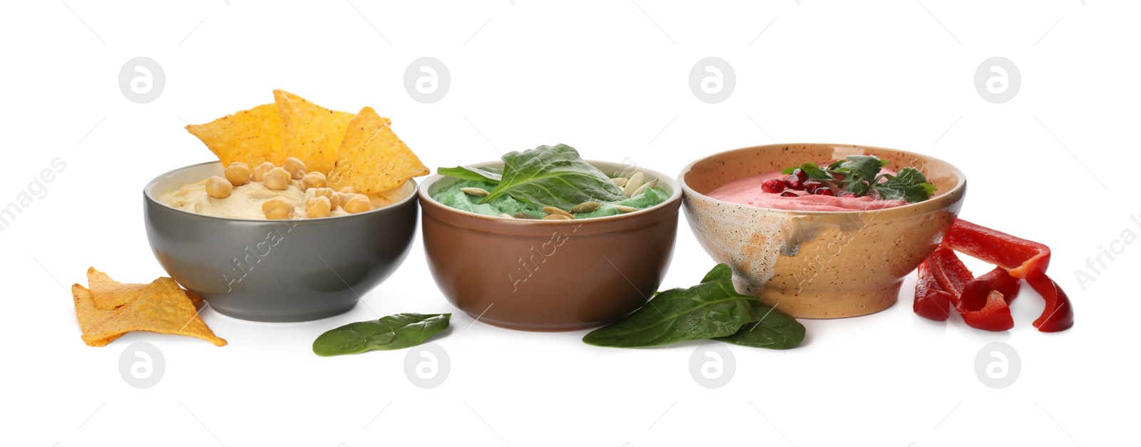 Photo of Different kinds of tasty hummus, nachos and ingredients on white background