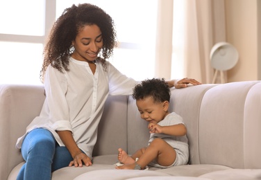 Photo of African-American woman with her baby in living room. Happiness of motherhood