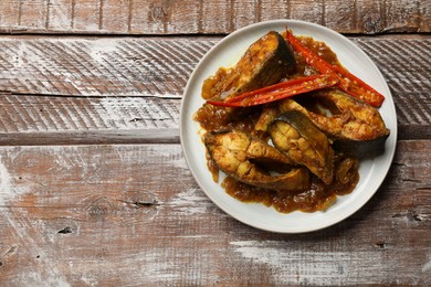 Photo of Tasty Indian fish curry on wooden table, top view. Space for text