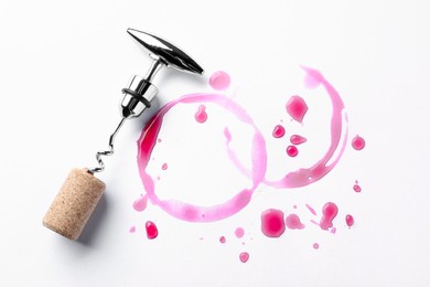 Photo of Wine stains, corkscrew and stopper on white background, top view