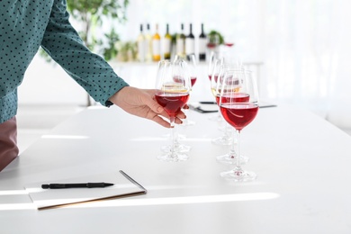 Photo of Young woman tasting delicious wine at table indoors