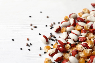 Photo of Mixed vegetable seeds on white wooden background, closeup