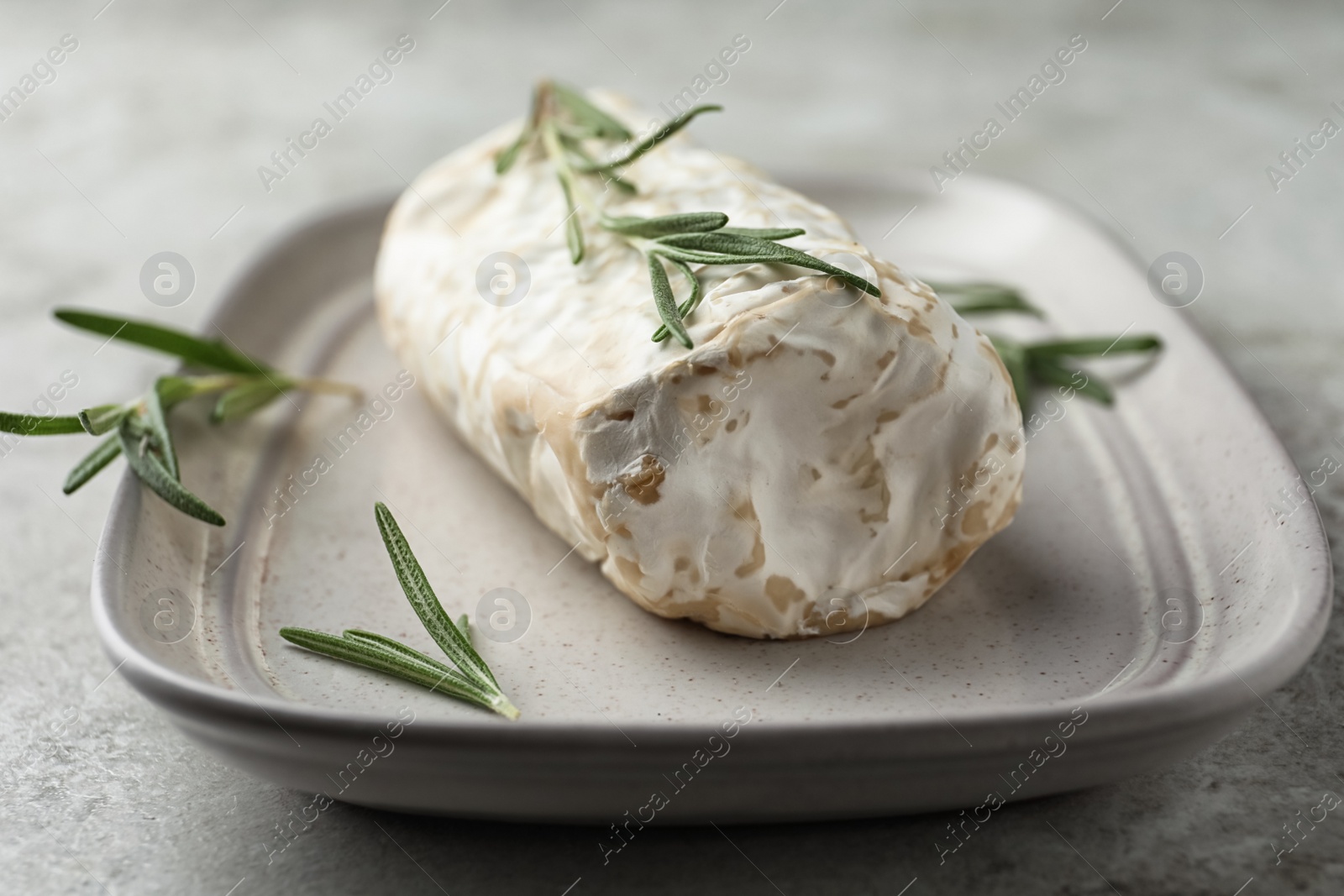 Photo of Delicious fresh goat cheese with rosemary on light grey table, closeup