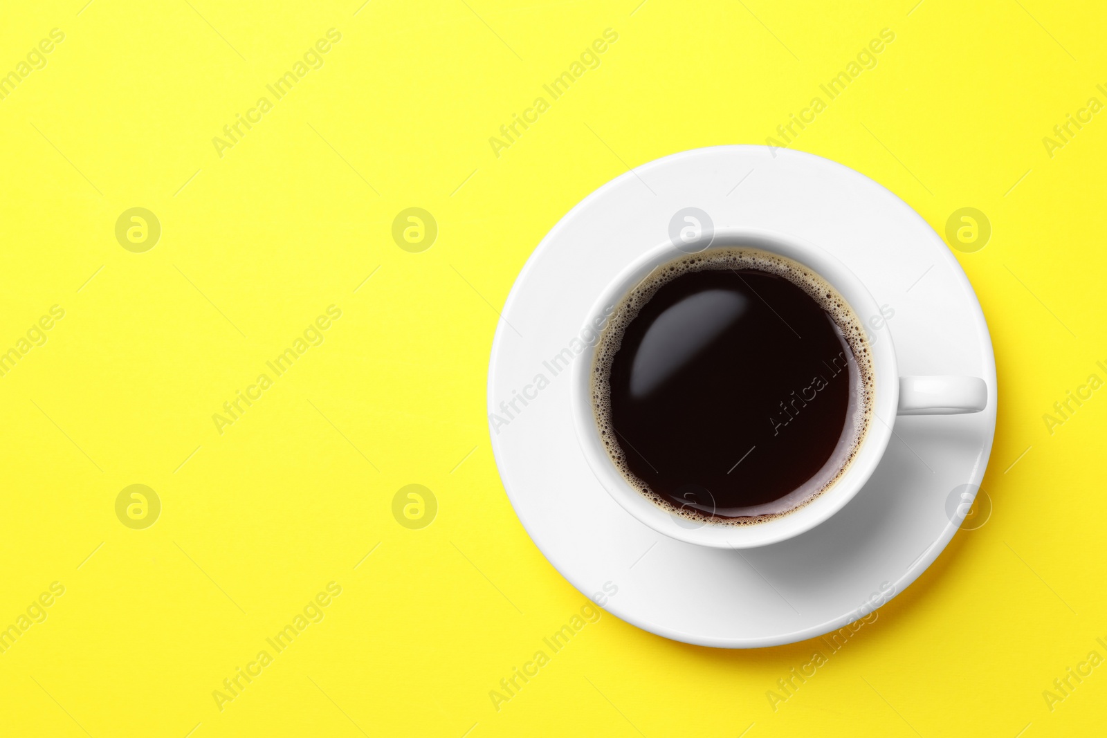 Photo of Cup of aromatic coffee on yellow background, top view. Space for text