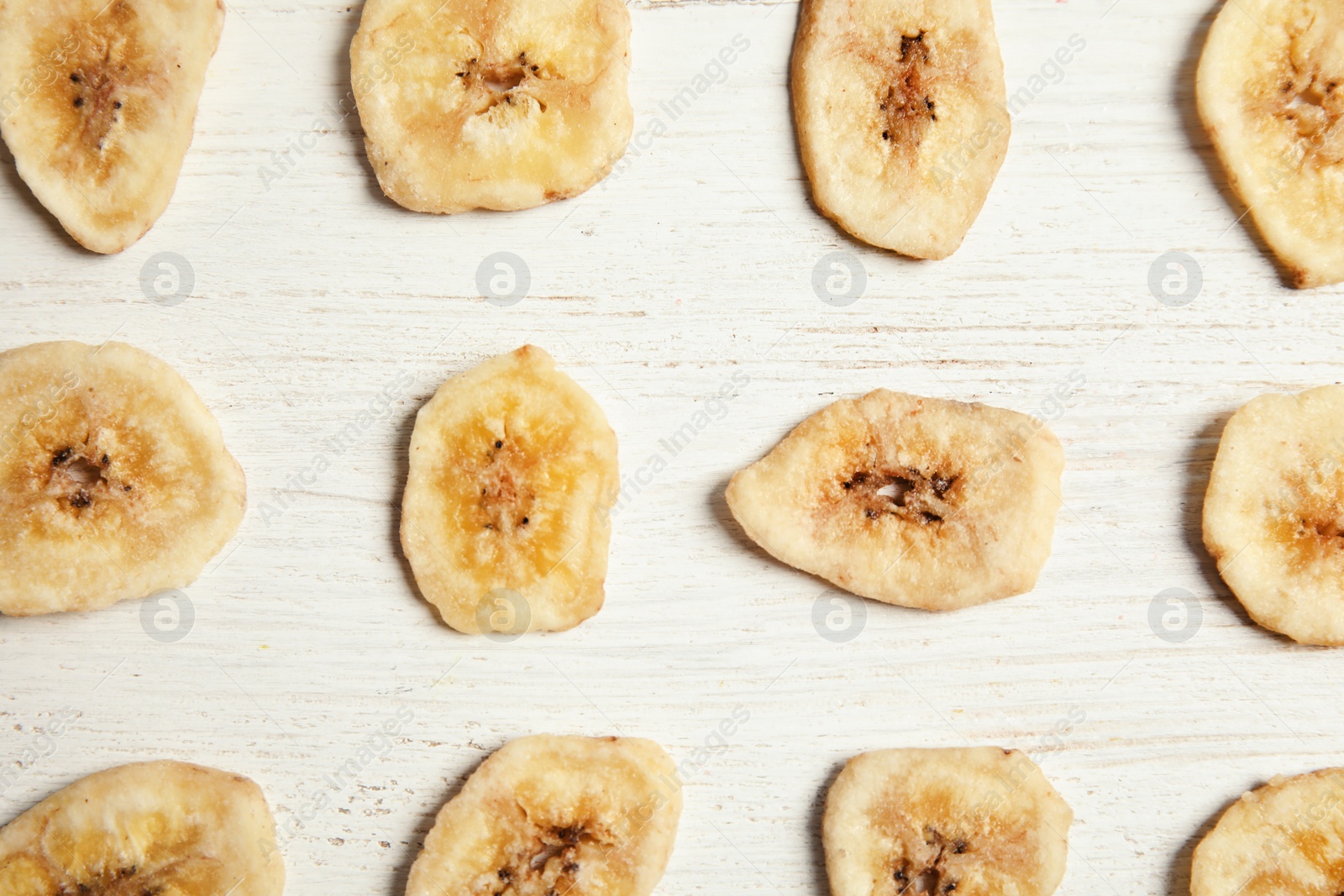 Photo of Flat lay composition with banana slices on wooden table. Dried fruit as healthy snack