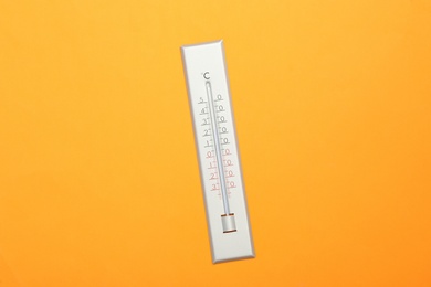 Weather thermometer on orange background, top view