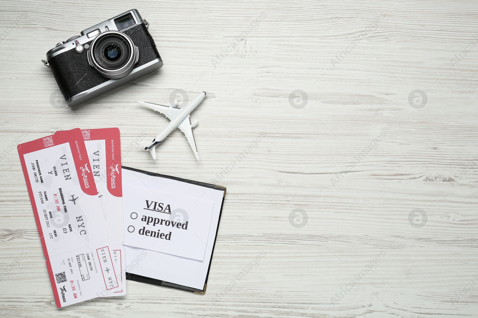 Photo of Flat lay composition with passport, toy plane and tickets on white wooden background, space for text. Visa receiving