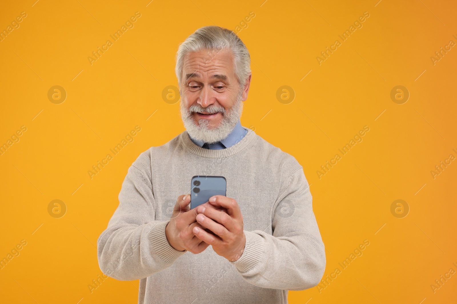 Photo of Happy senior man using smartphone on yellow background