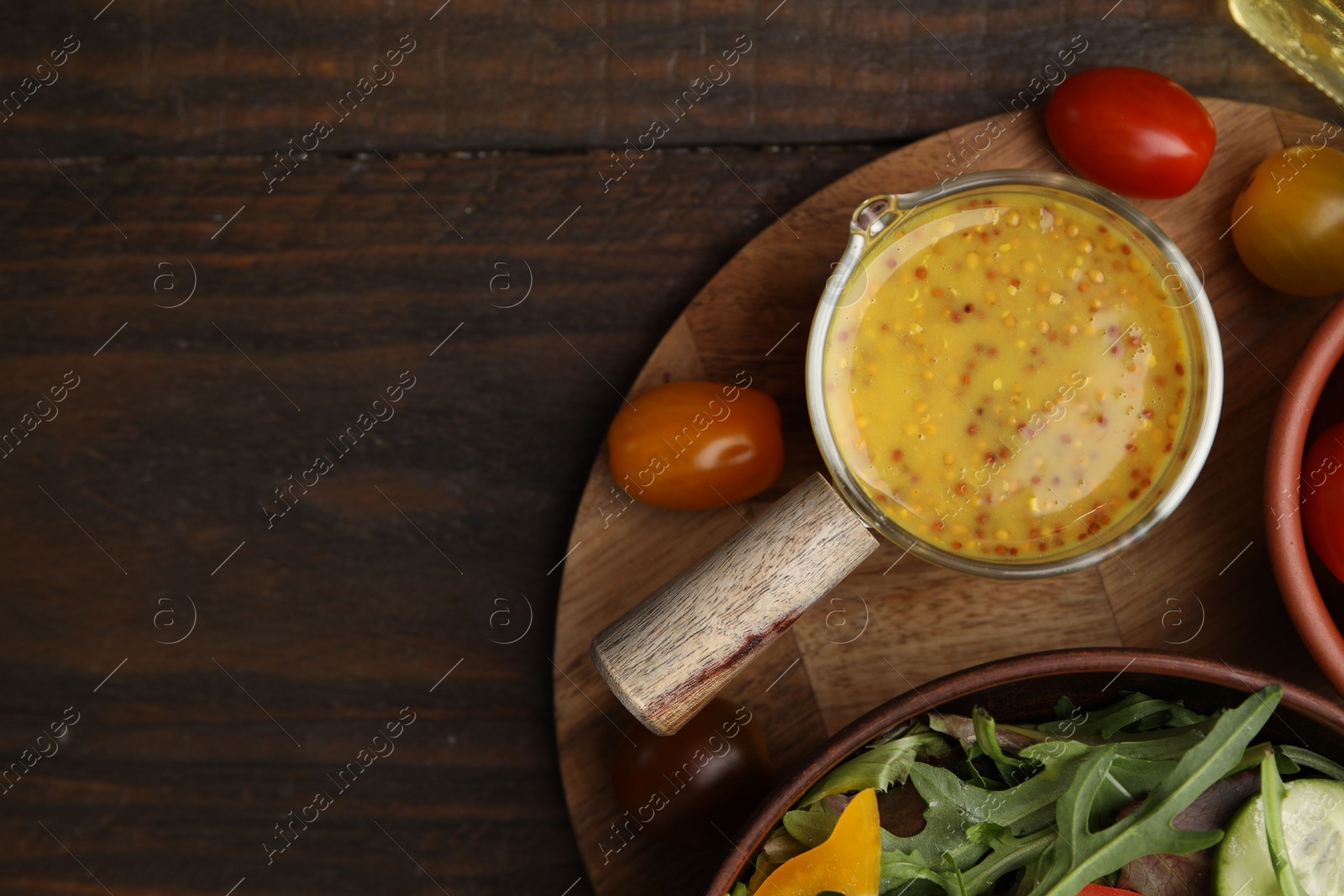 Photo of Tasty vinegar based sauce (Vinaigrette), salad and tomatoes on wooden table, top view. Space for text