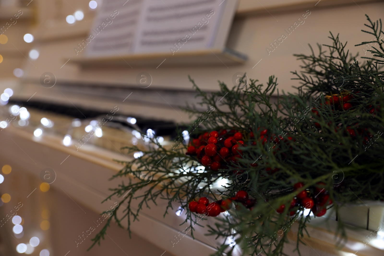 Photo of Fir branches with berries on piano keys indoors, space for text. Christmas music