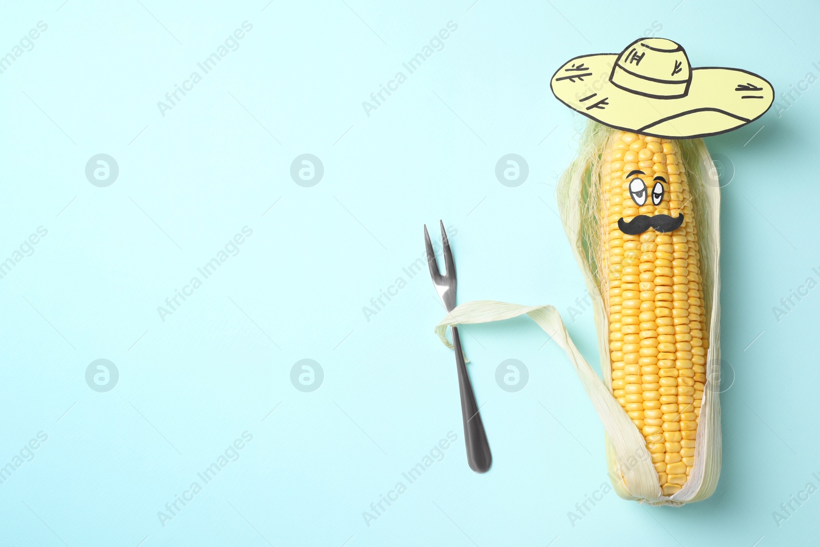 Photo of Mexican man of corncob, paper hat and fork on light blue background, top view. Space for text