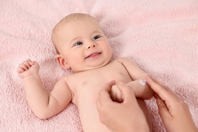 Woman applying body cream onto baby`s skin on bed, top view