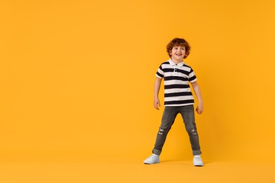 Happy little boy dancing on yellow background. Space for text