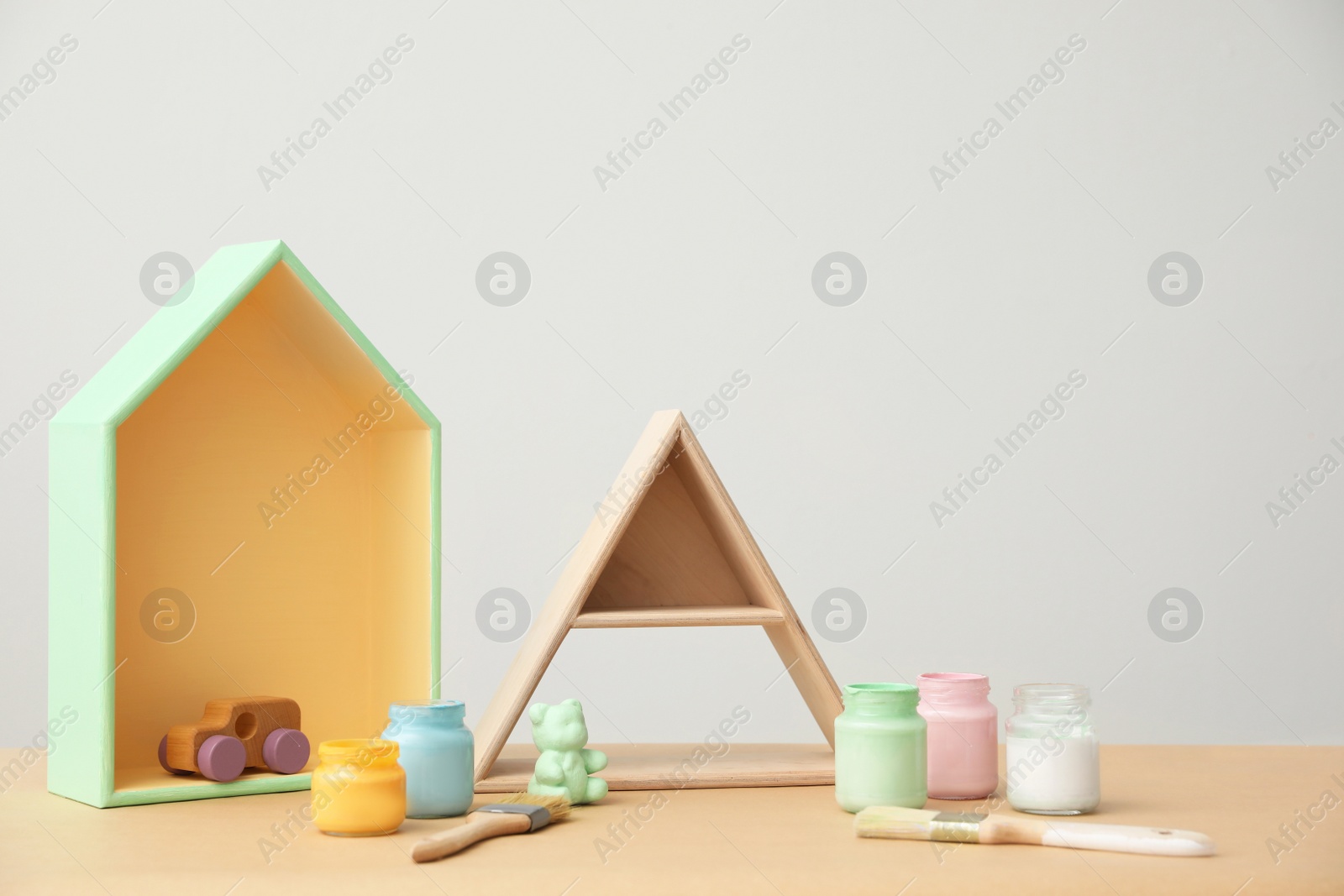 Photo of Composition with jars of paints and shelves on wooden table. Interior elements