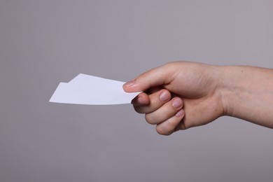 Photo of Woman holding paper cards on grey background, closeup. Mockup for design