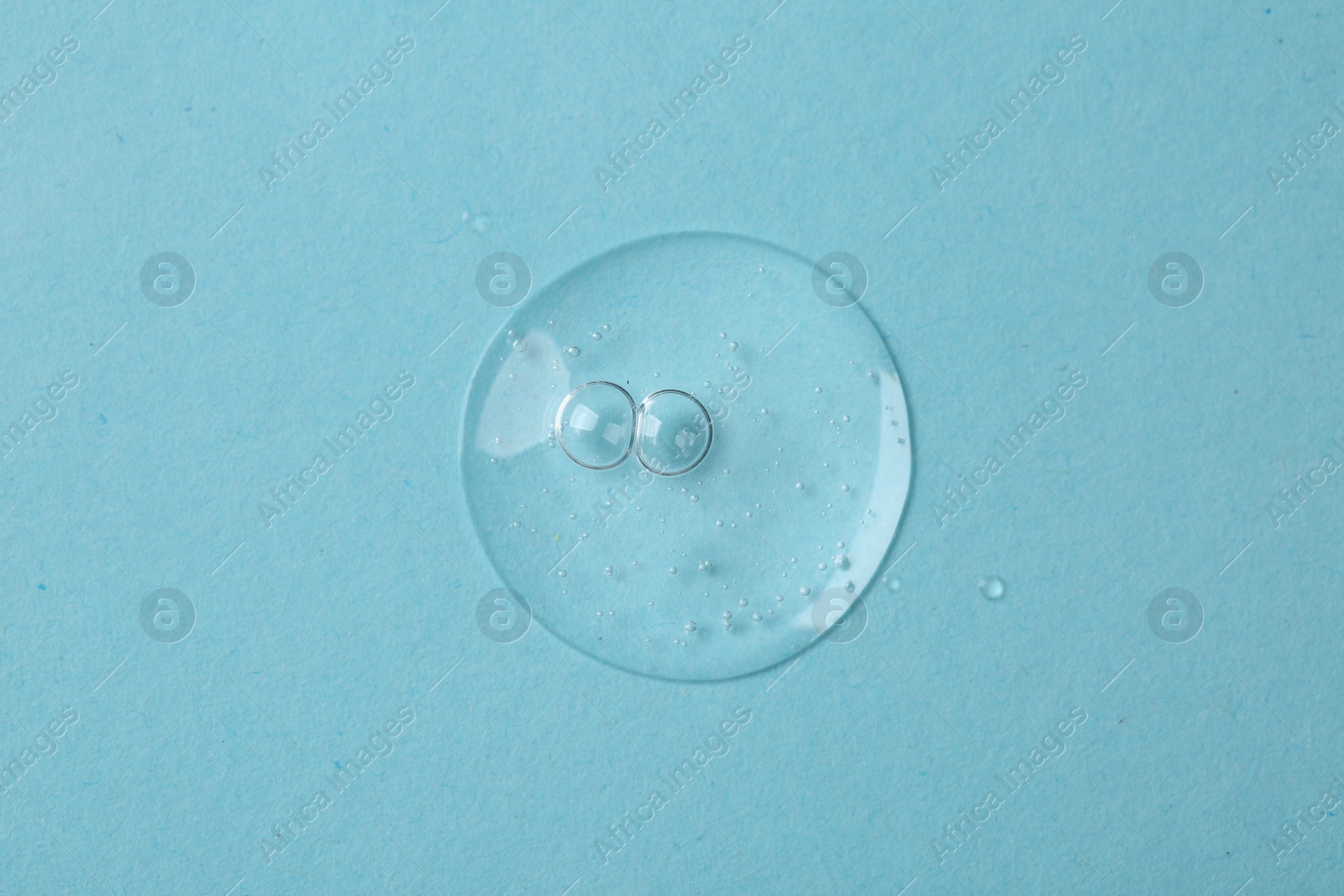 Photo of Sample of cosmetic serum on light blue background, top view