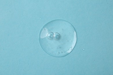 Photo of Sample of cosmetic serum on light blue background, top view