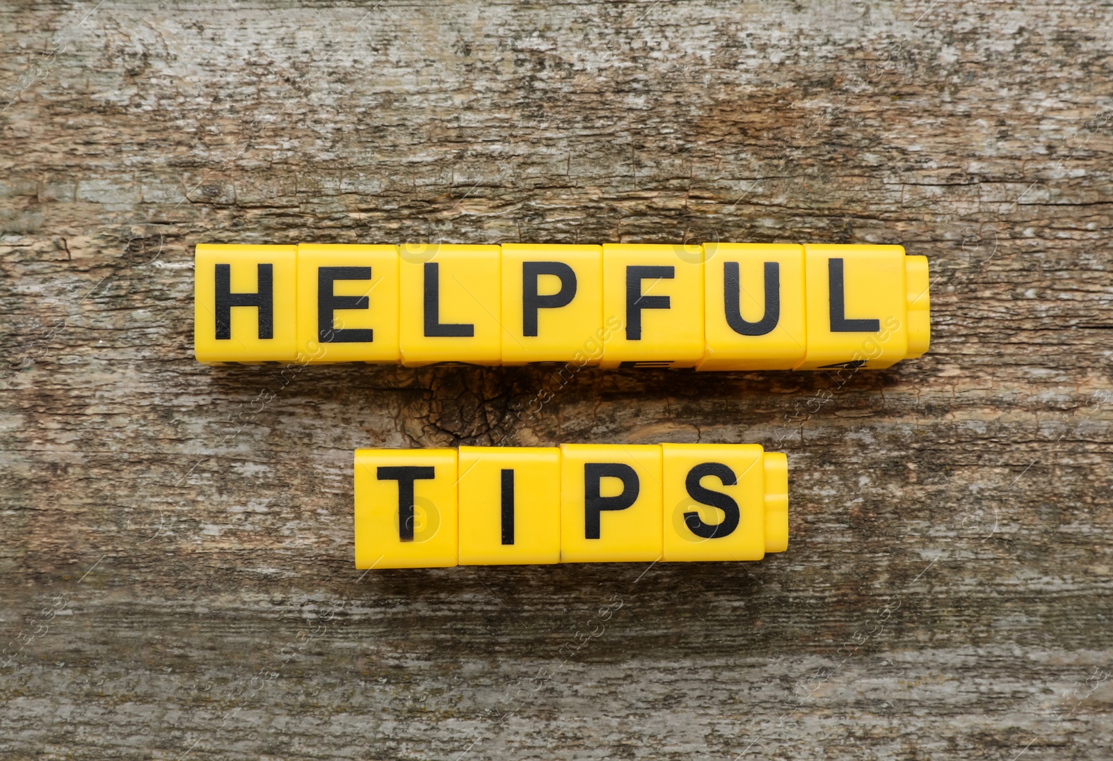 Photo of Text Helpful Tips made of yellow cubes with letters on wooden table, top view