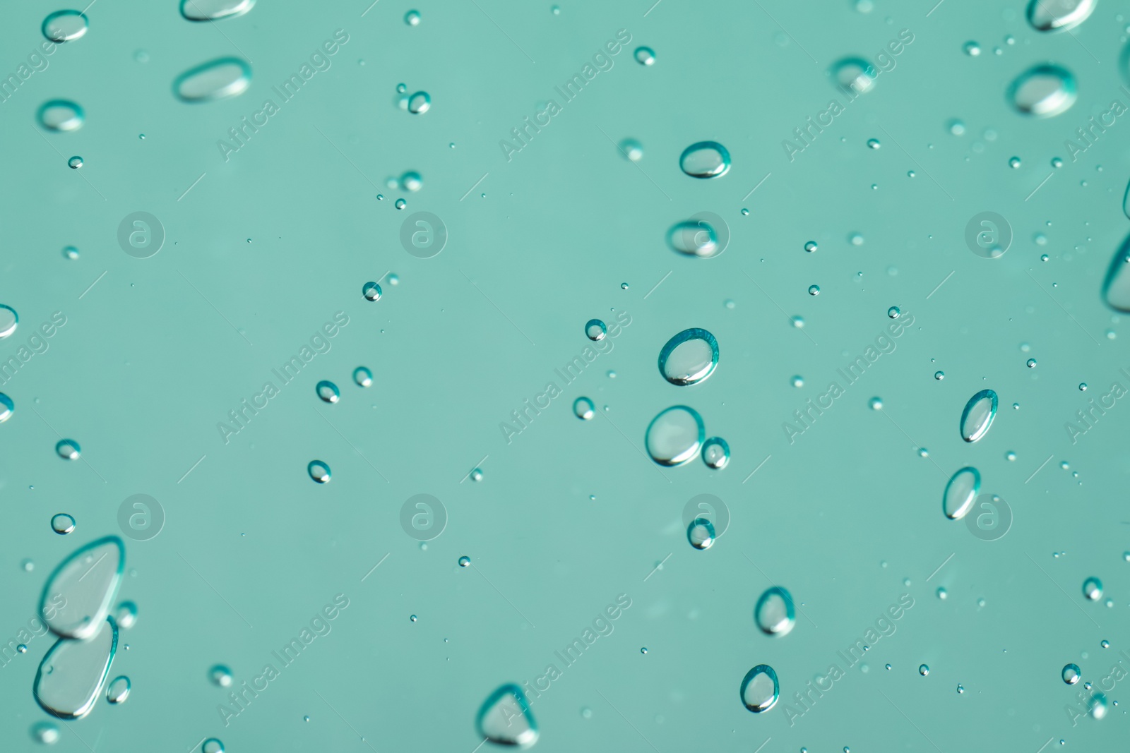 Photo of Serum drops on light blue background, closeup