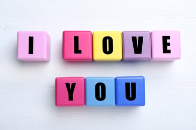 Colorful cubes with words I Love You on white wooden background, flat lay