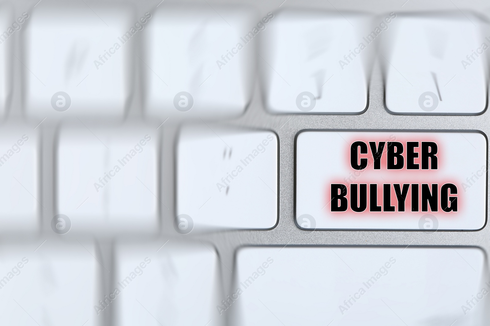 Image of Top view of defocused laptop keyboard and phrase CYBER BULLYING on white button, closeup