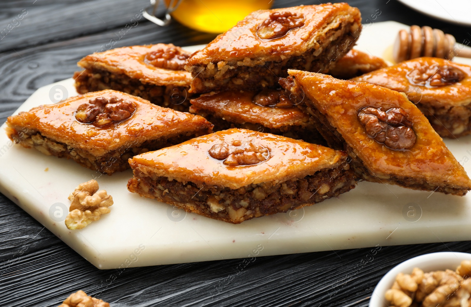 Photo of Delicious sweet baklava with walnuts on black wooden table, closeup