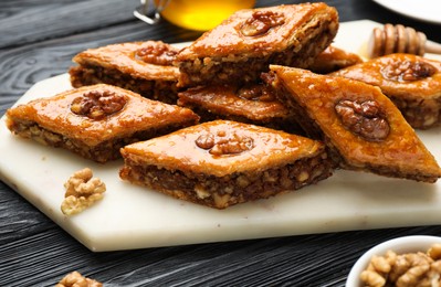 Delicious sweet baklava with walnuts on black wooden table, closeup