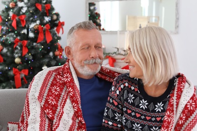 Photo of Happy mature couple with plaid at home. Christmas celebration