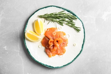 Photo of Plate with fresh sliced salmon fillet, lemon and rosemary on table