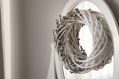 Photo of Wreath with pussy willow branches on mirror indoors. Space for text
