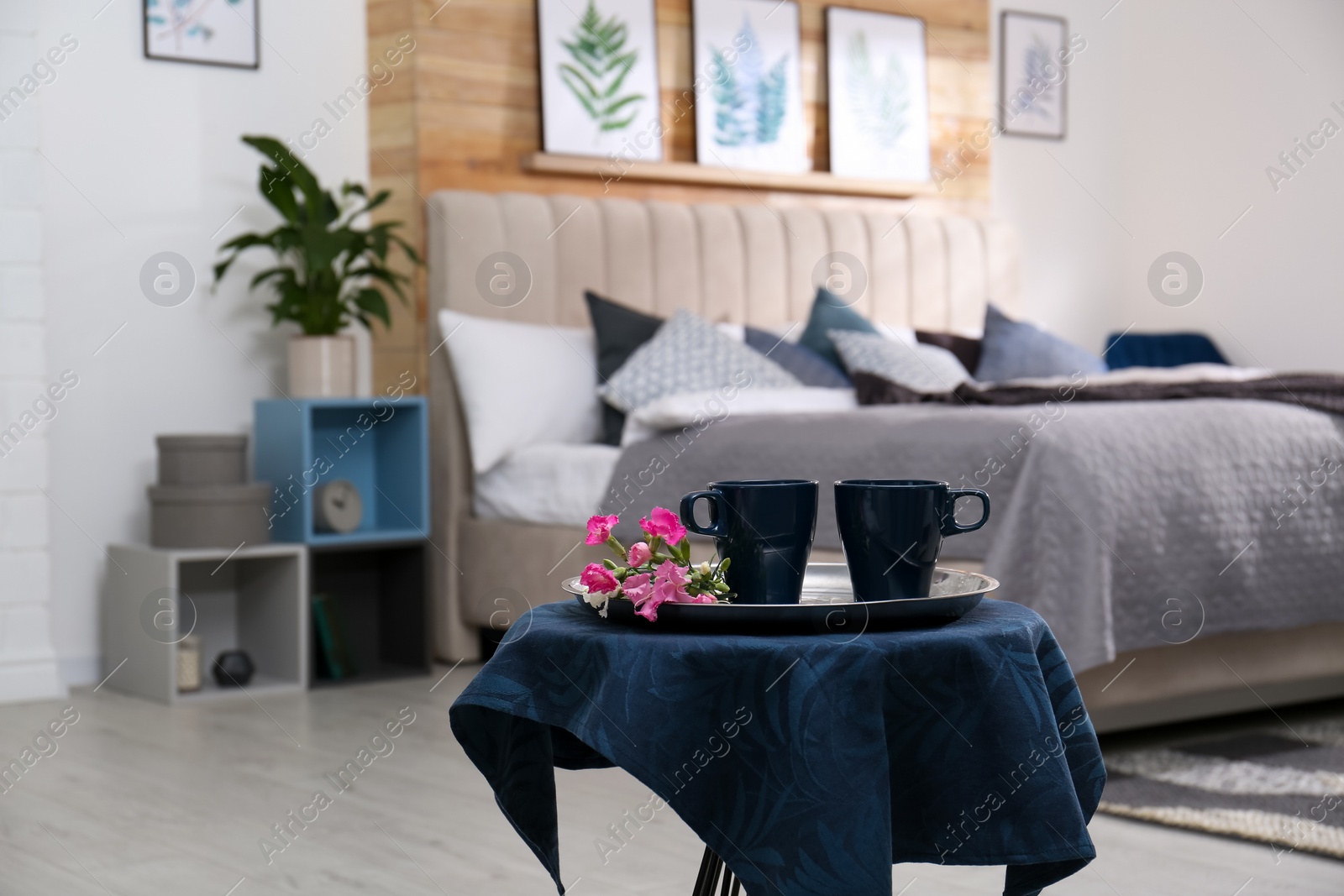 Photo of Blue cups and flowers on table in bedroom