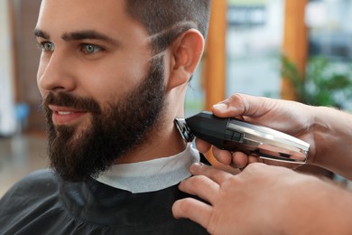 Photo of Professional hairdresser working with client in barbershop, closeup