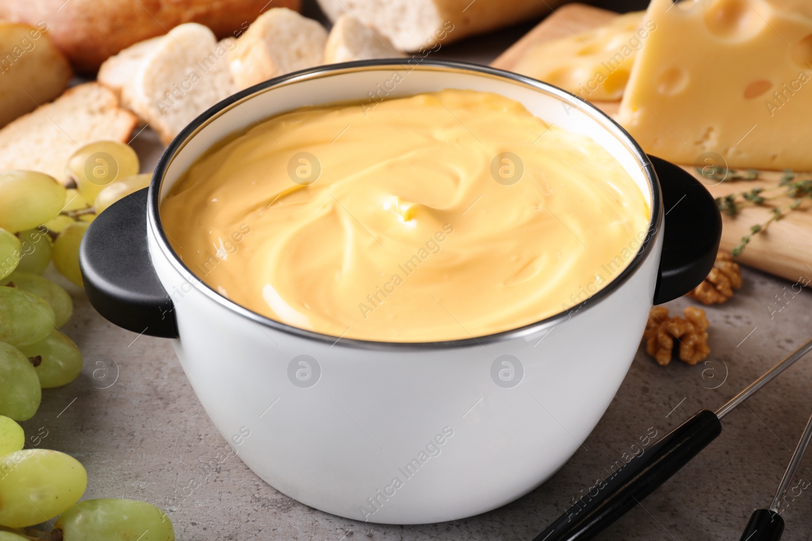 Photo of Pot with delicious cheese fondue on gray table