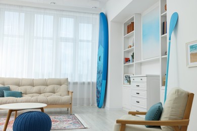 SUP board and modern furniture in stylish living room. Interior design