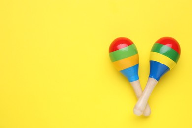 Photo of Colorful maracas on yellow background, flat lay with space for text. Musical instrument