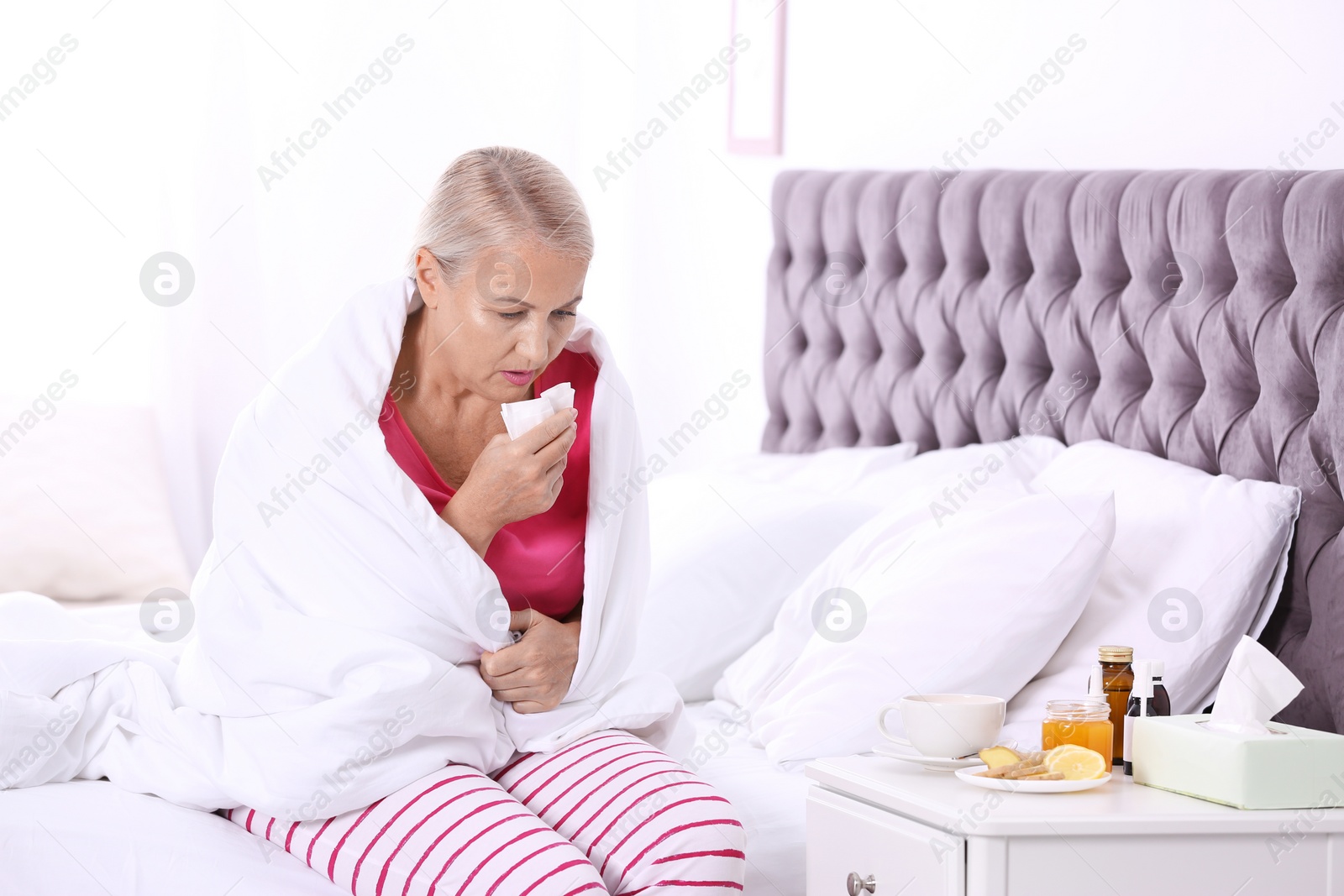 Photo of Ill mature woman suffering from cough in bed