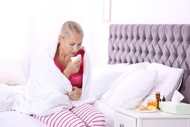 Ill mature woman suffering from cough in bed