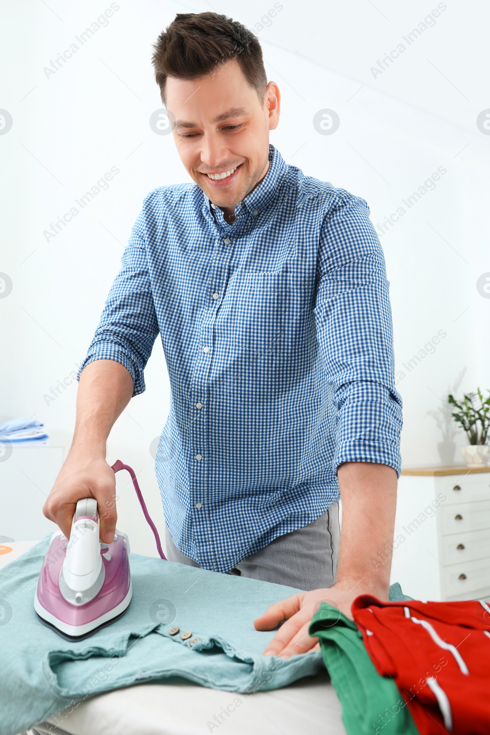 Photo of Man ironing clothes on board at home