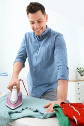 Man ironing clothes on board at home