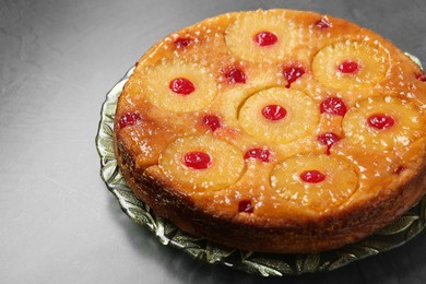 Photo of Plate with tasty pineapple cake on grey textured table, closeup. Space for text