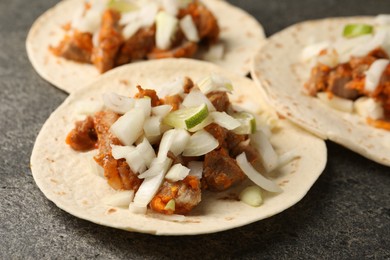 Delicious tacos with vegetables, meat and lime on grey textured table, closeup