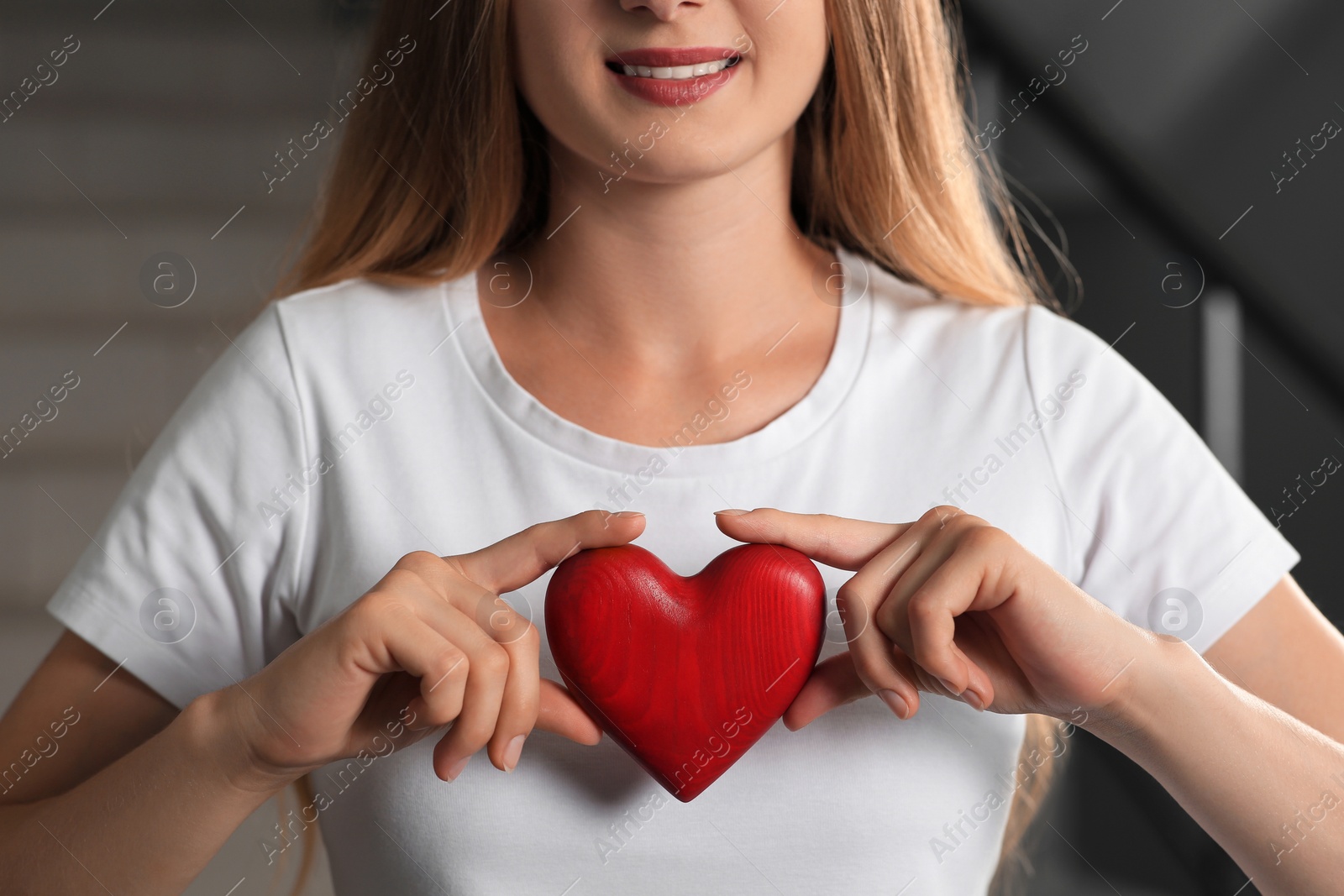 Photo of Young woman holding red heart indoors, closeup. Volunteer concept