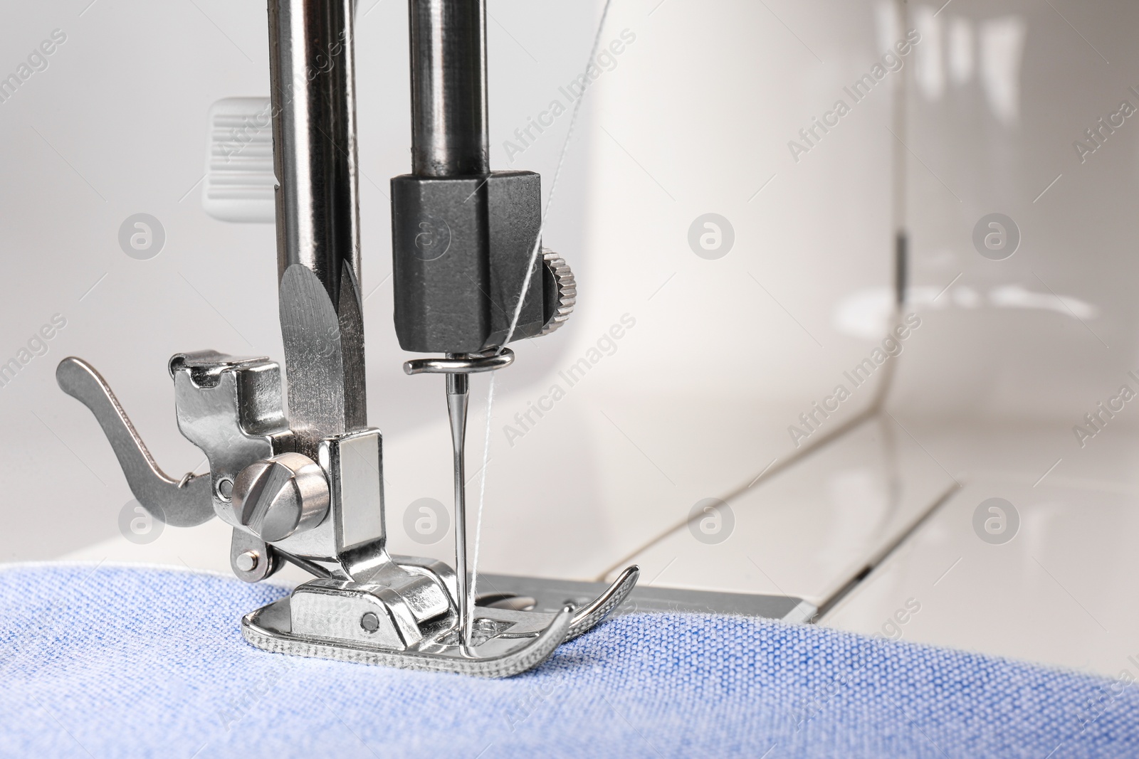 Photo of Sewing machine with light blue cloth, closeup